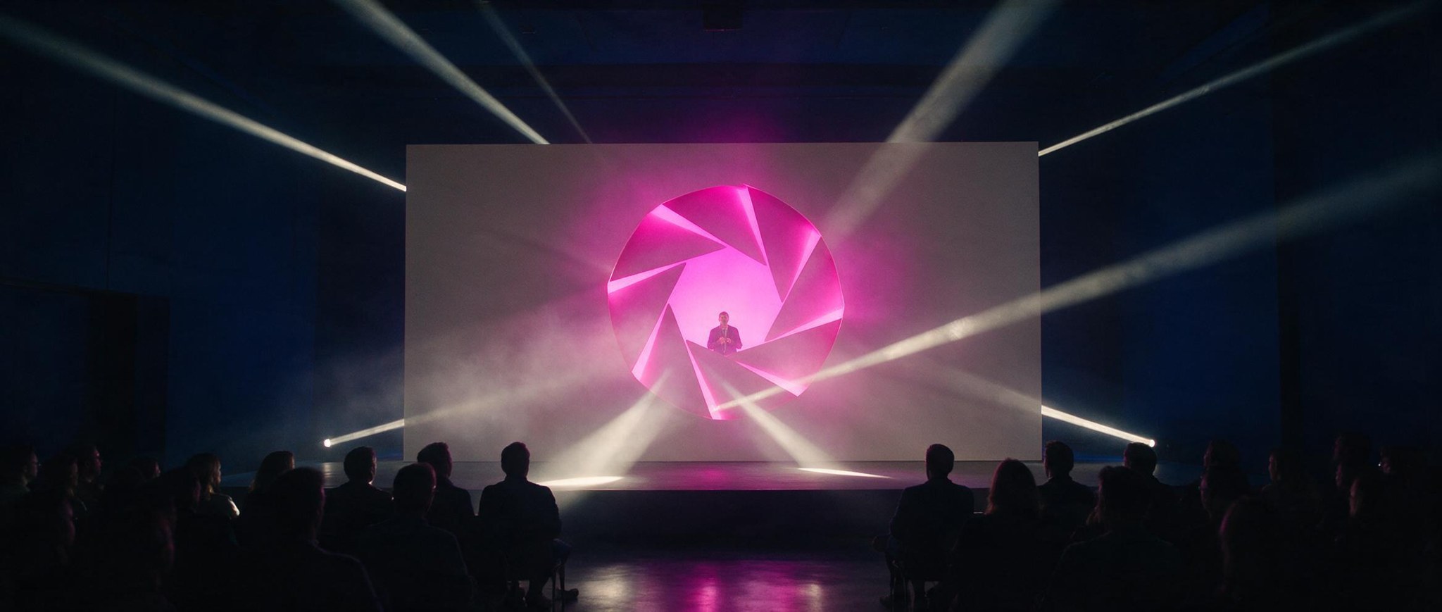 Cenografia do palco: diafragma vazado magenta que vira janela interna para a passagem de pessoas