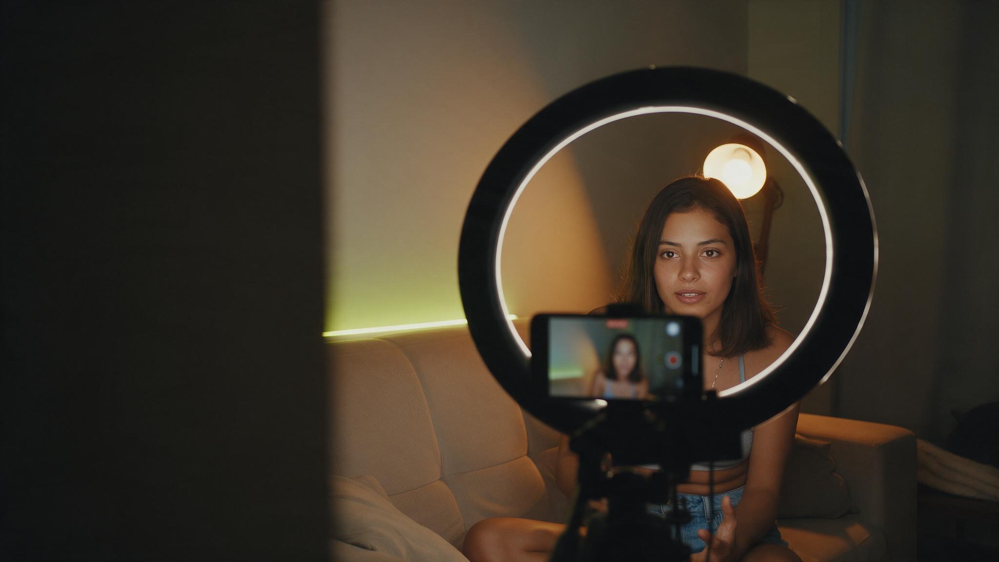 Creator diante do ring light, com o próprio rosto na tela do celular