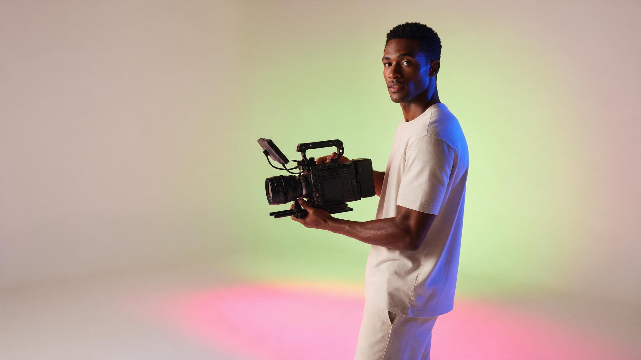Clima claro: homem com câmera de cinema num set branco com géis limão, rosa e azul
